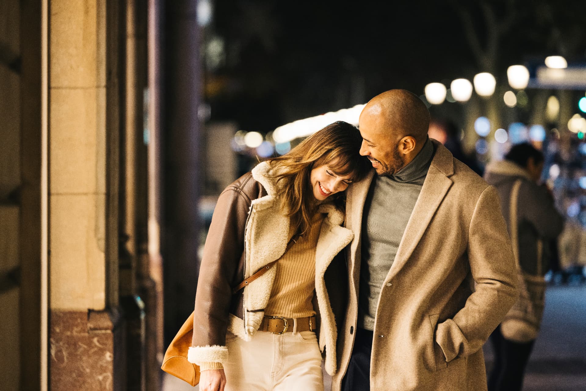 Couple laughing together on a city street at night