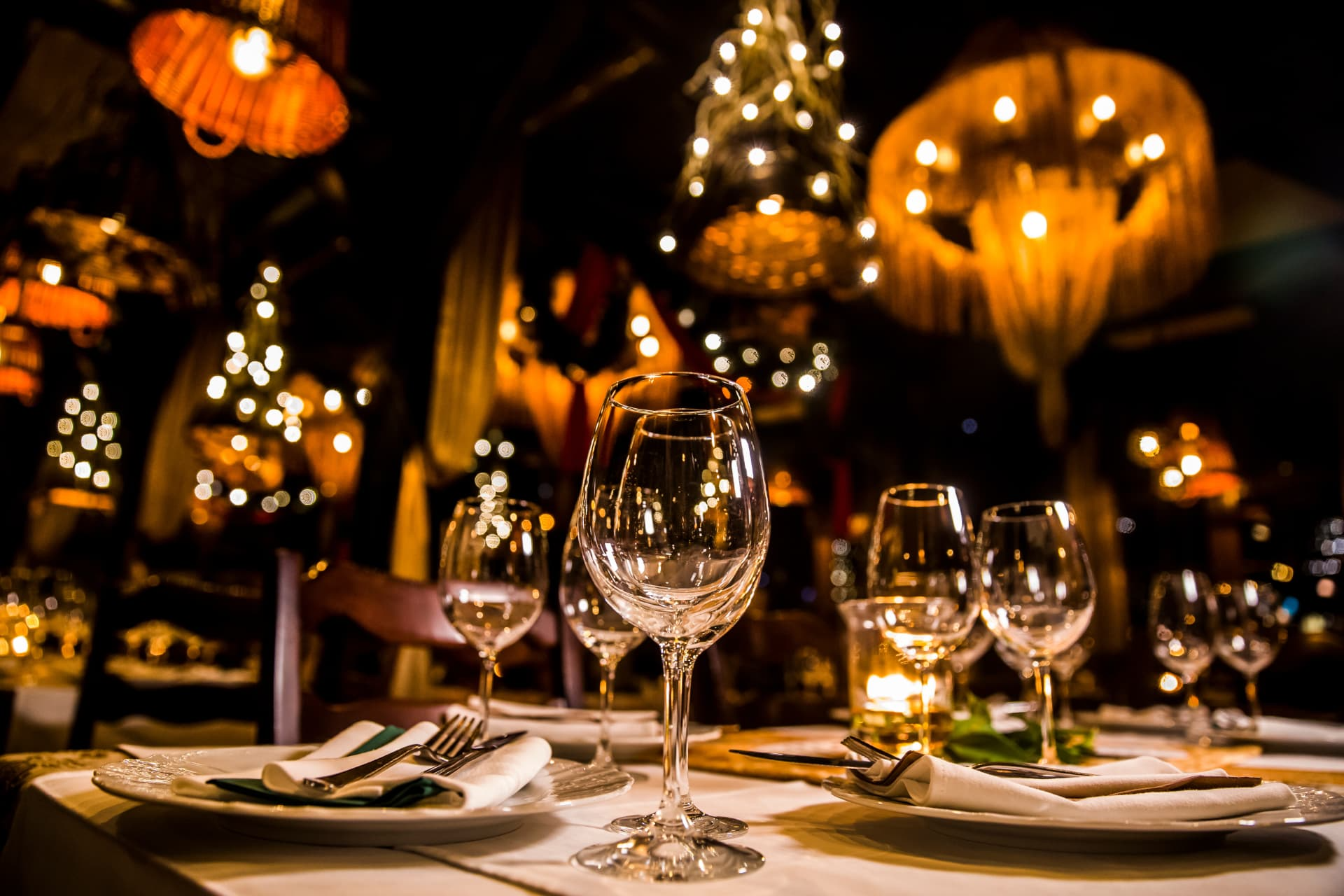 An elegant candlelit dinner table set with crystal wine glasses, fine linens and warm ambient lights — the romantic atmosphere of Amor en DC!